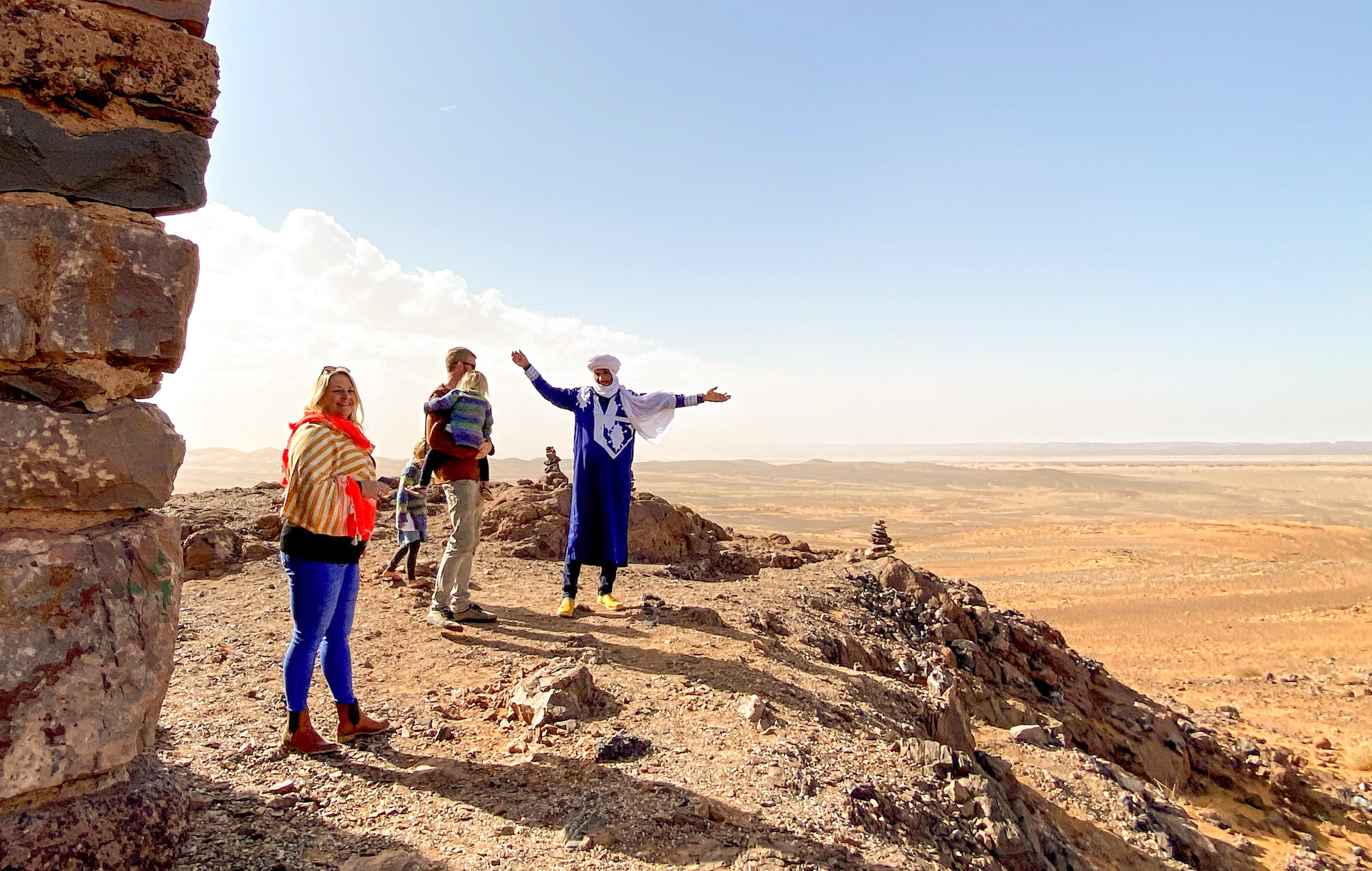 Family with a Berber tour guide stood at a desert viewpoint outside Merzouga, Morocco
