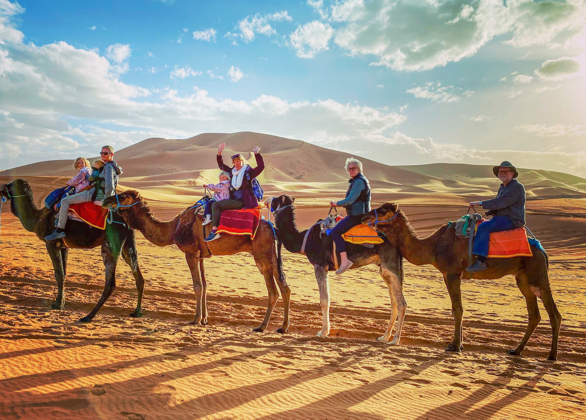 Family riding camels to a desert camp at Merzouga, Morocco