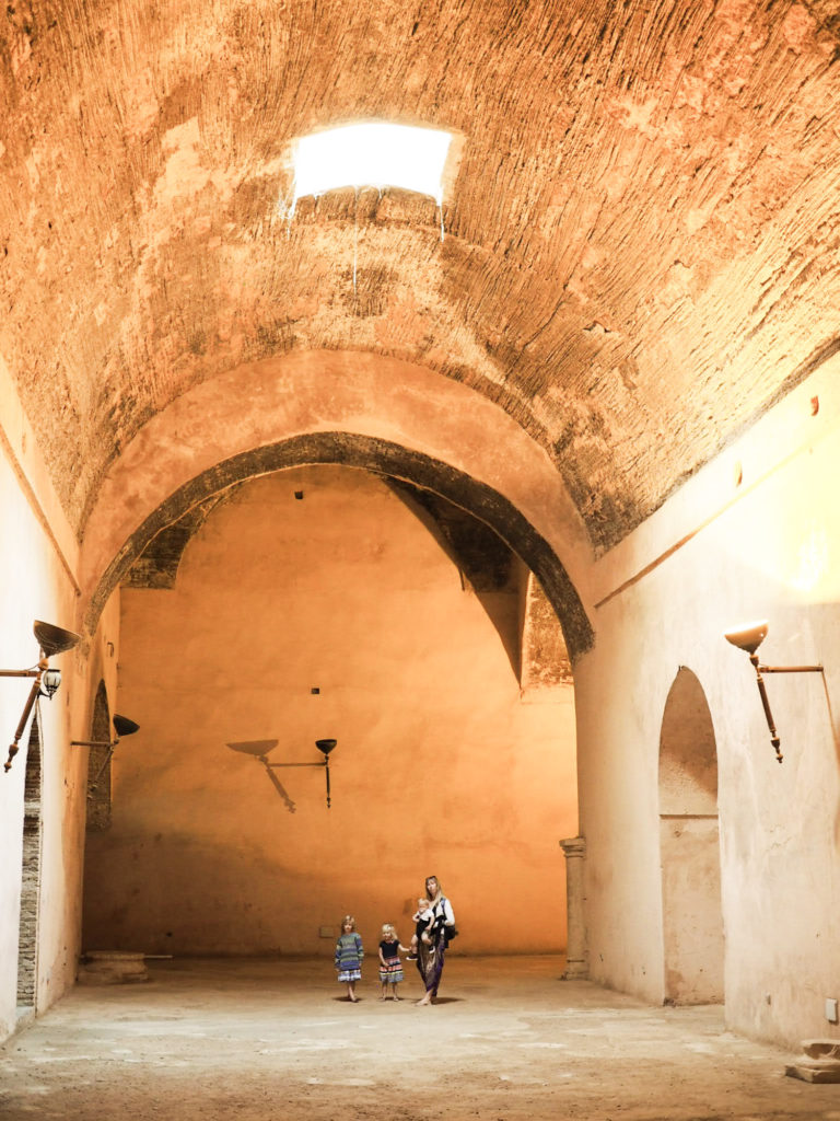 Family stood under high valted ceiling at the entrance to former Royal stables at Meknes, Morocco