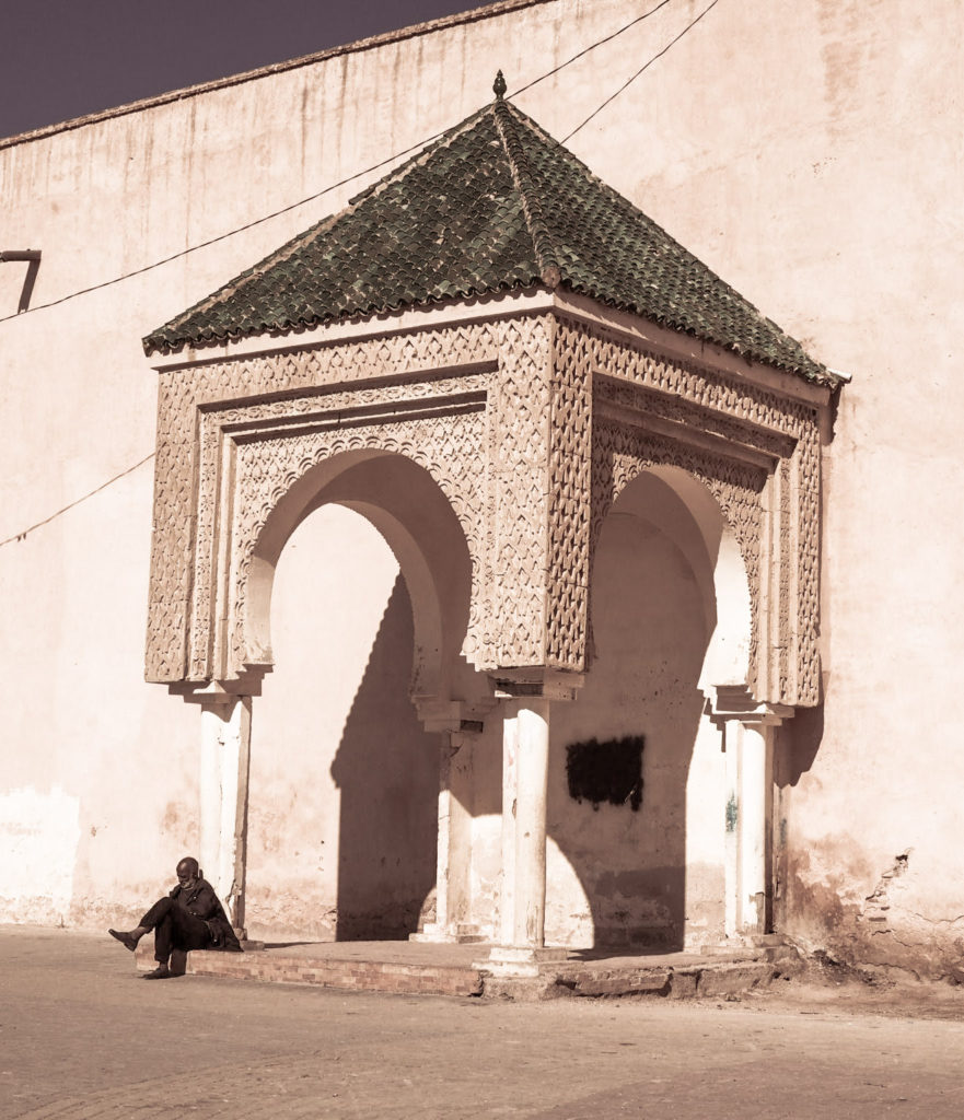 Man sat by a decorative city wall feature in Meknes, Morocco