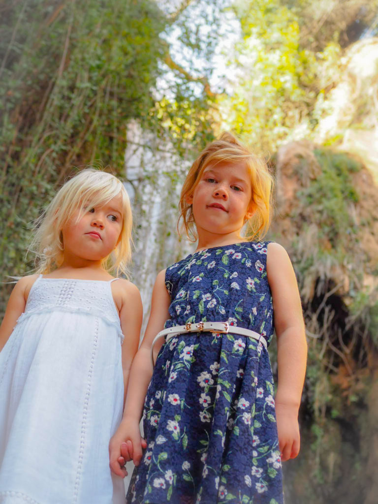 Close up of 2 small girls, stood in front of a waterfall at Sefrou, Morocco