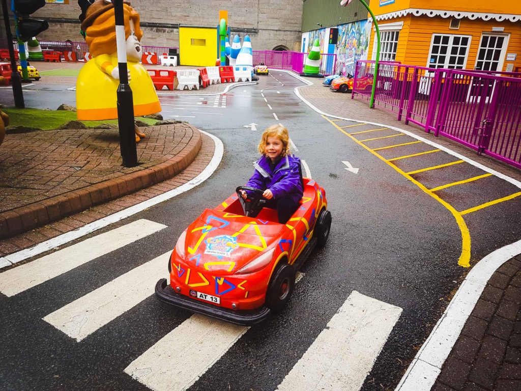 Small girl sat inside a child's electric car, on a ride at Alton Towers theme park