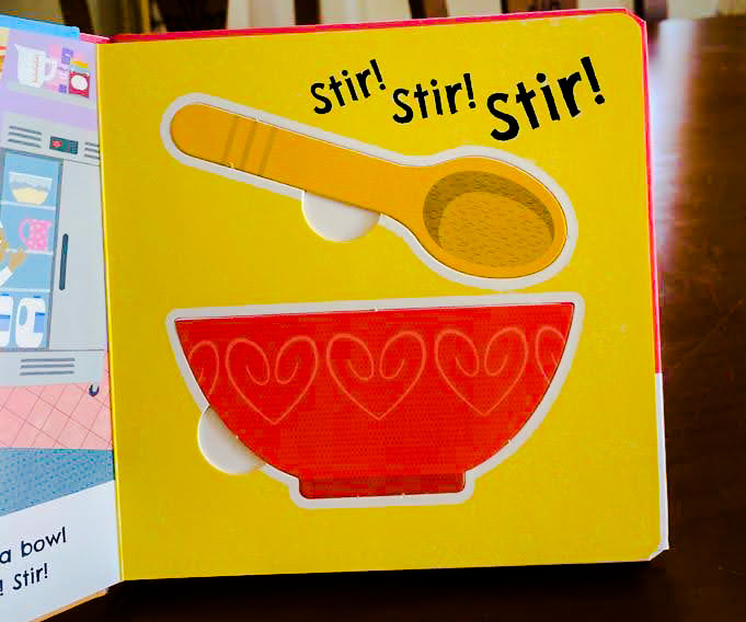 View of an inside page of a children's book, showing a colourful bowl and spoon and the words 'stir, stir, stir'