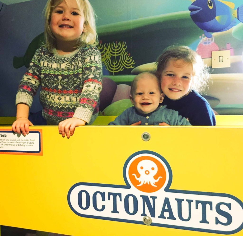 3 excited small children sat on a top bunk bed, in a 'Octonauts' themed room at the CBeebies Land Hotel