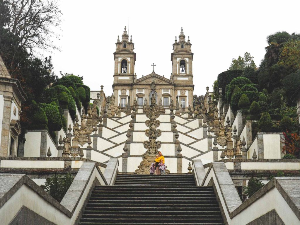 Family stood on a long staircase lined with statues, that leads up to the church on the hill at Sanctuary of Bom Jesus do Monte