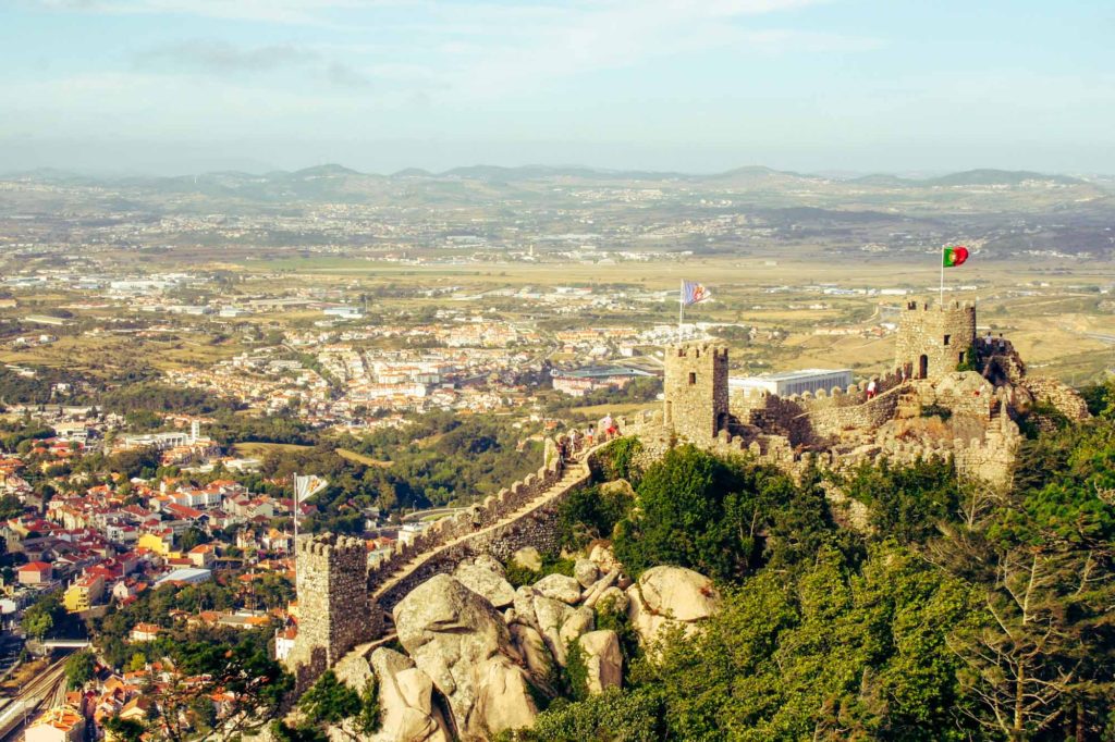 Expansive view from a panoramic viewpoint, with stone walls and ramparts of the Moorish Castle, Sintra, just below