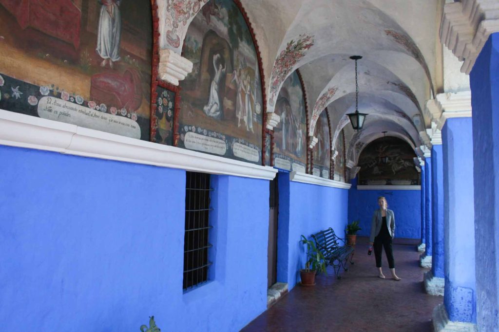 Lady stood in decorative blue painted cloisters in a monastery