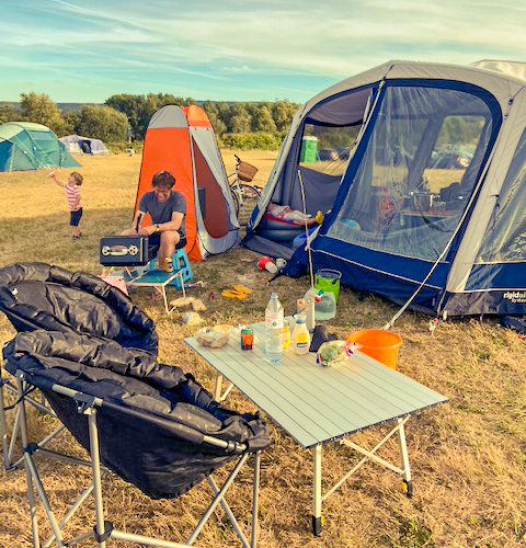 Man sat outside a large family tent in a field