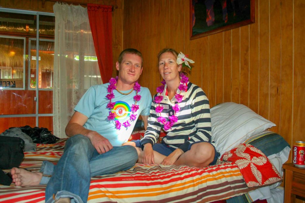 Couple sat on a bed with flower garlands around their necks