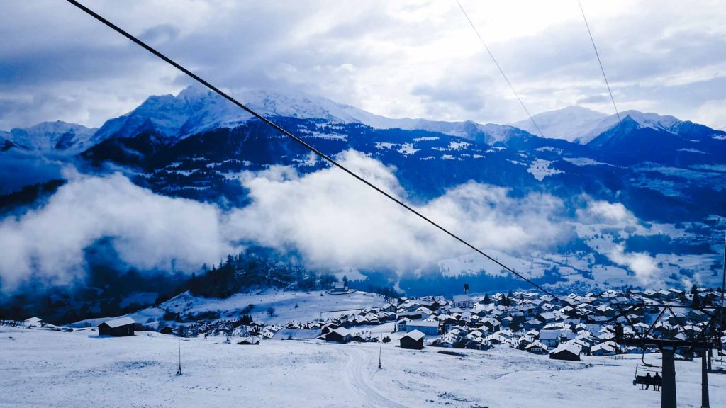 View down to a snowy Swiss valley with town, taken from riding a chairlift
