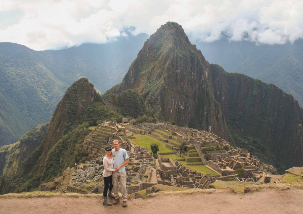 Couple stood at a mountain viewpoint in front of the lost Inca city of Machu Picchu