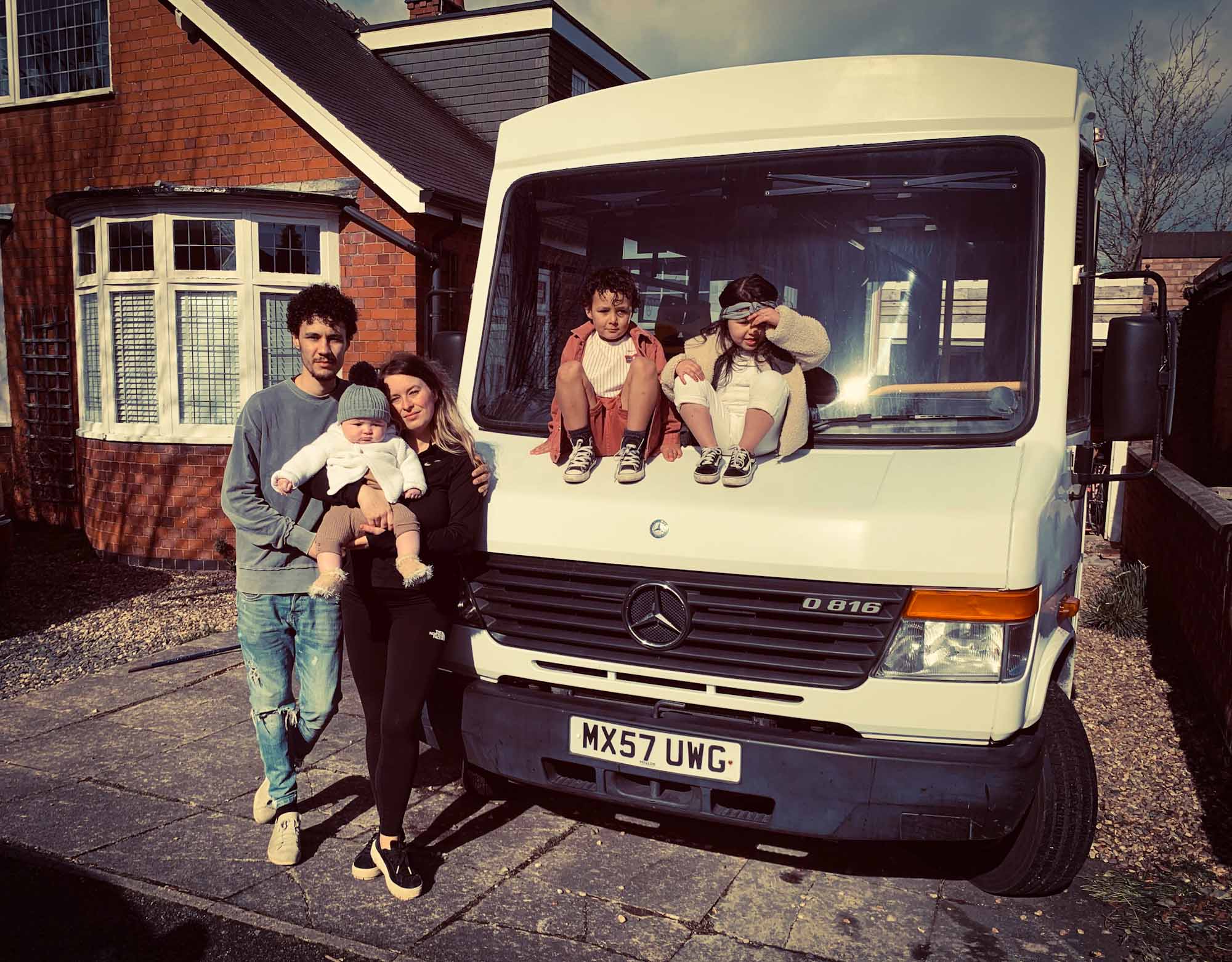 Family stood around a Mercedes Vario bus, parked on their house driveway