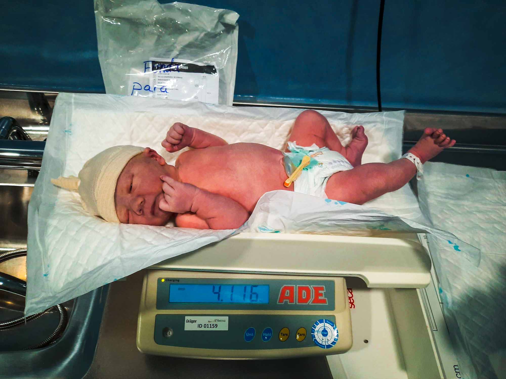 A newborn baby, lying on weighing scales