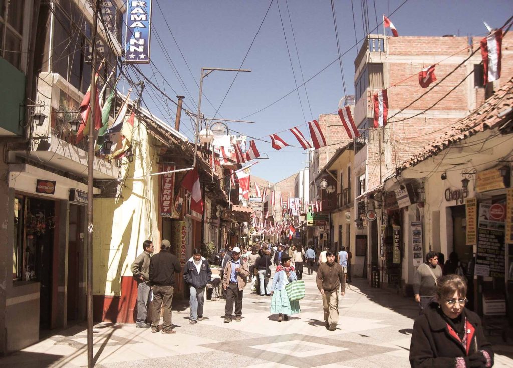 Looking down a busy pedestrianised street, with bunting of Peruvian flags above