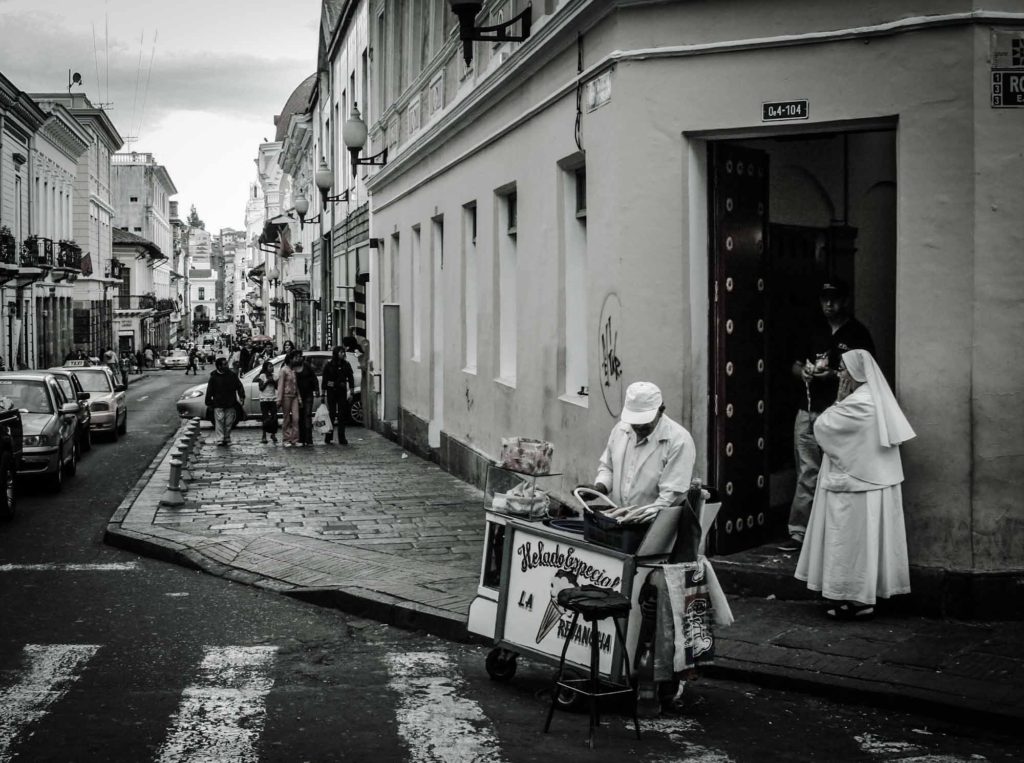 Man selling ice creams from a cart, with nun stood behind, in Quito, Ecuador