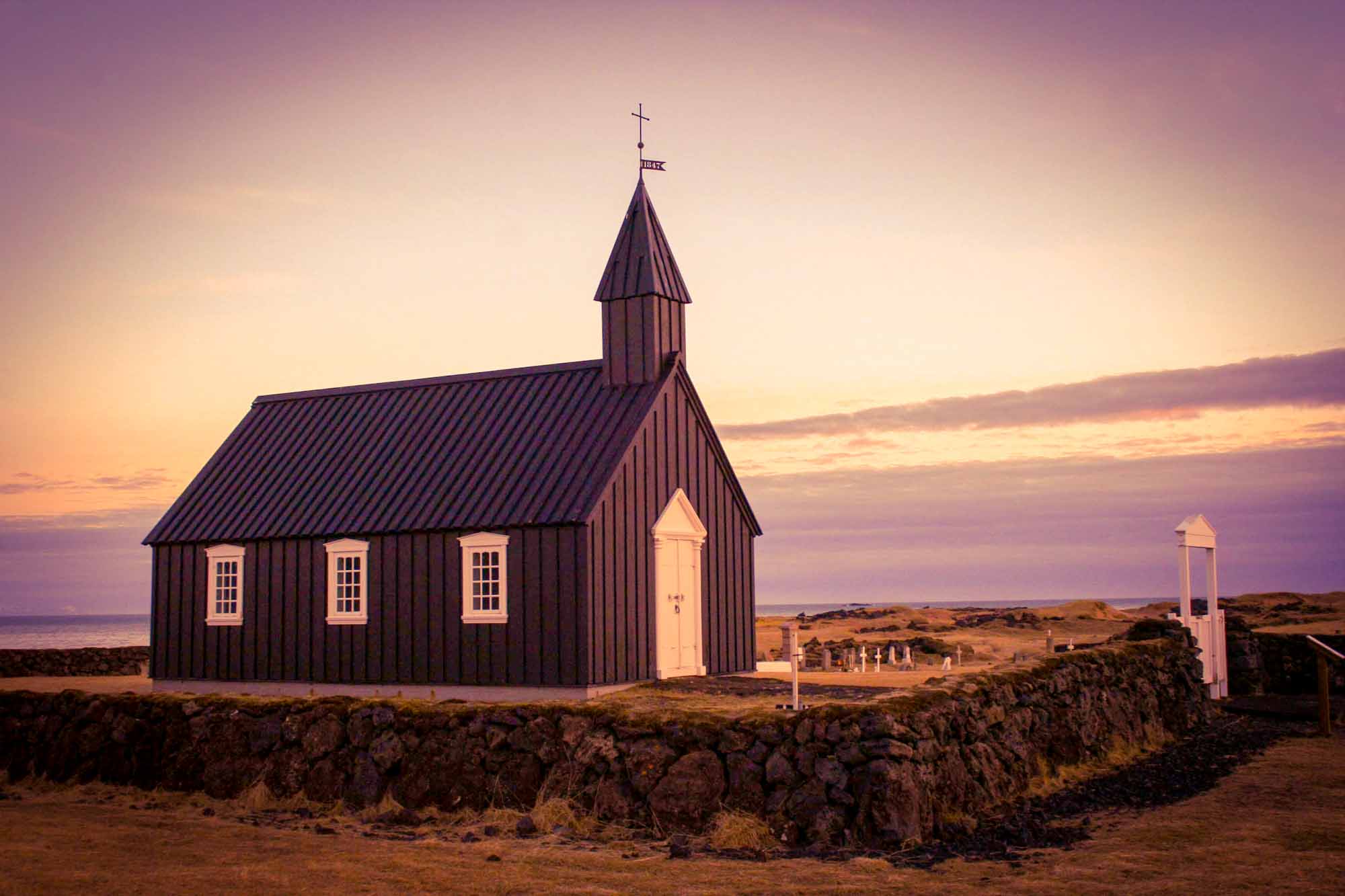 Small black painted wooden church, at sunrise