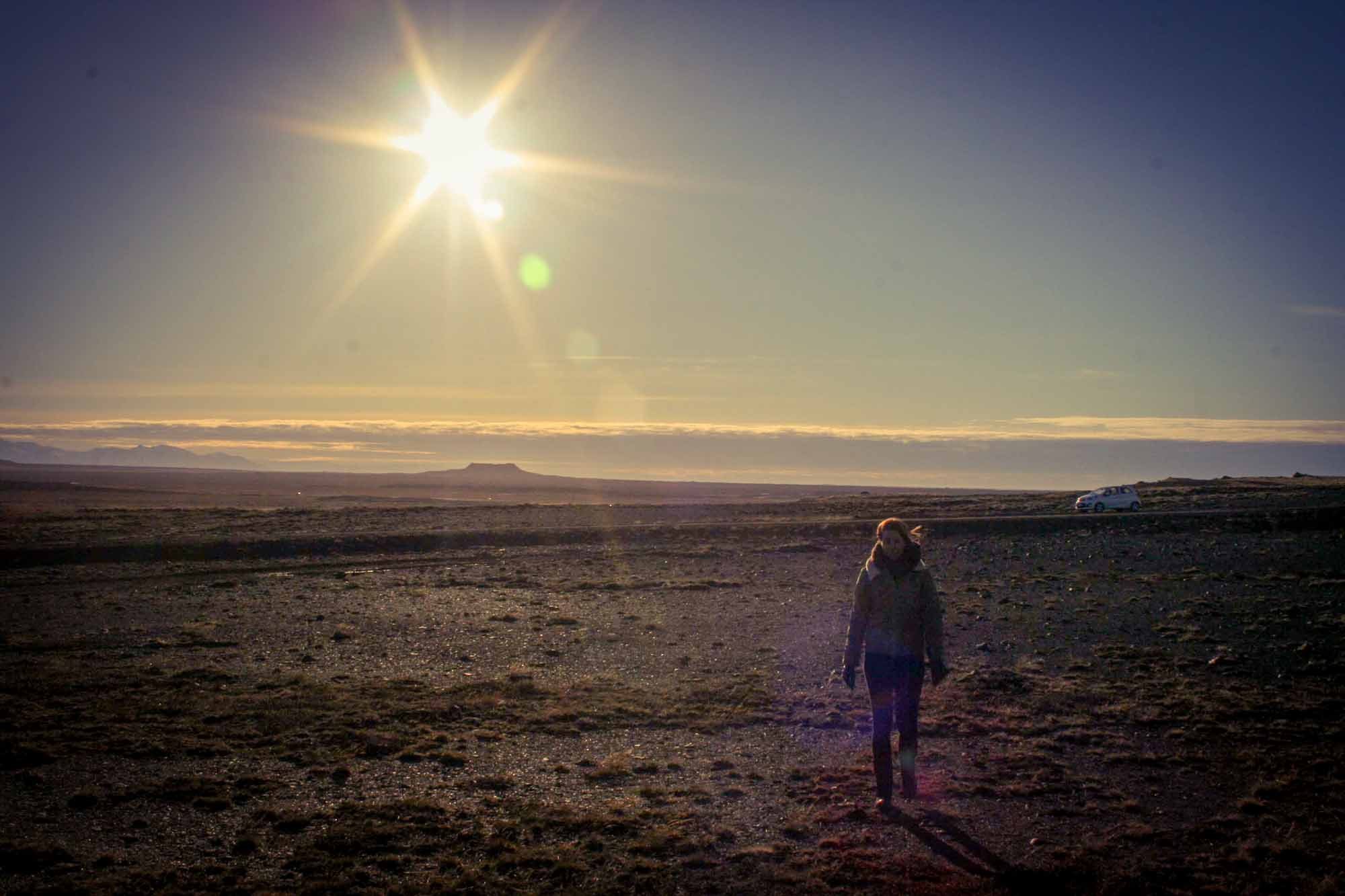 Lady walking away from a car on the Snæfellsnes Peninsula, Iceland, with sun low in the sky