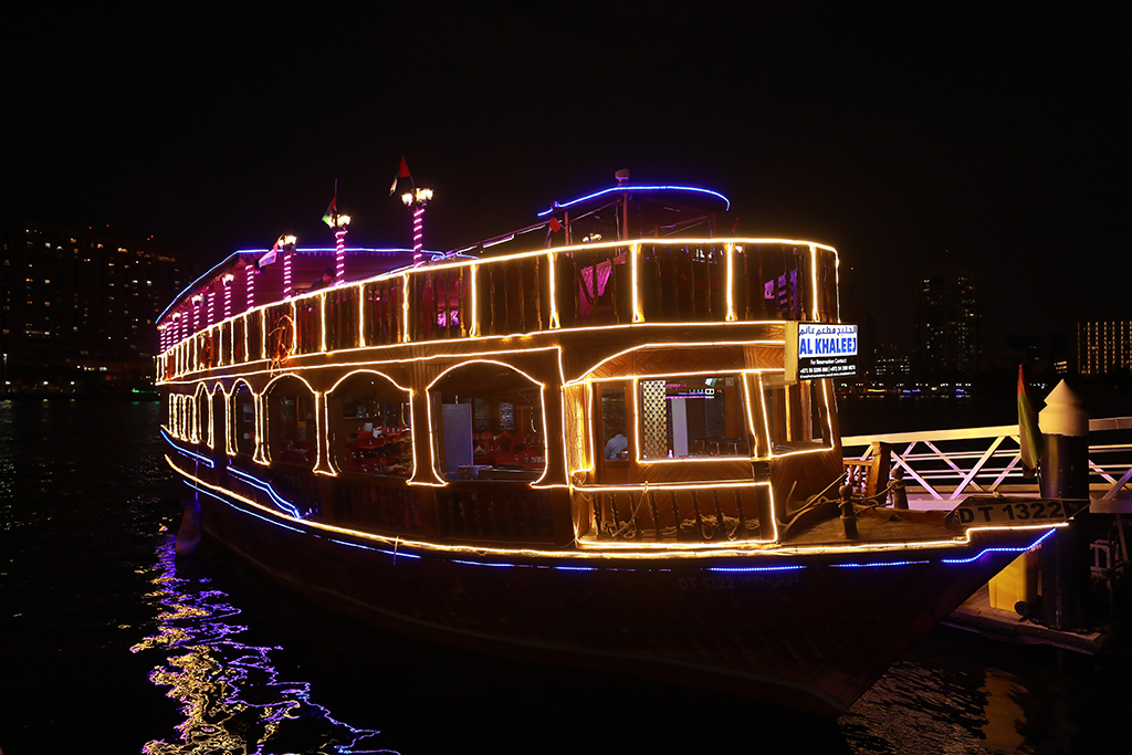 A river boat at night, lit up with colourful string lights