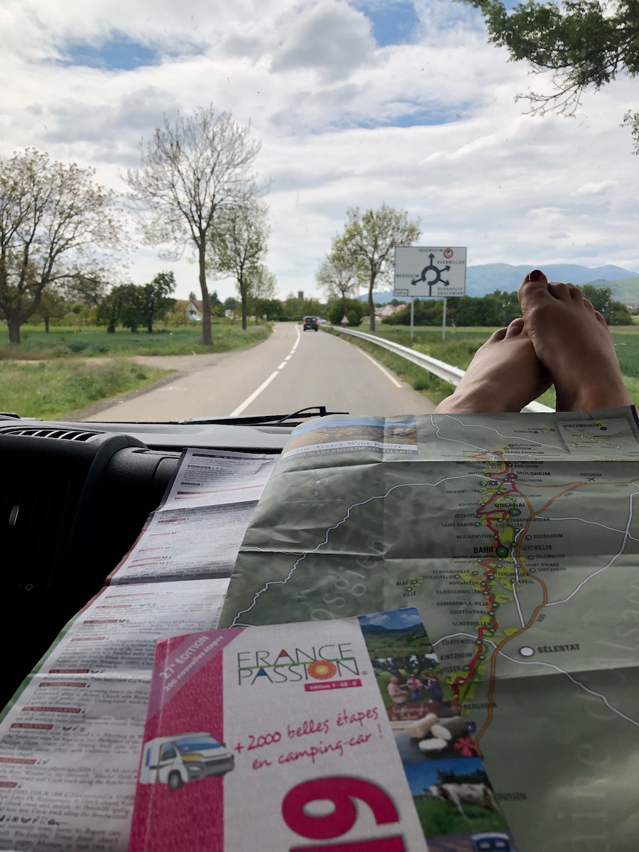 View out of a campervan windscreen while driving, with a France Passion book on the dashboard