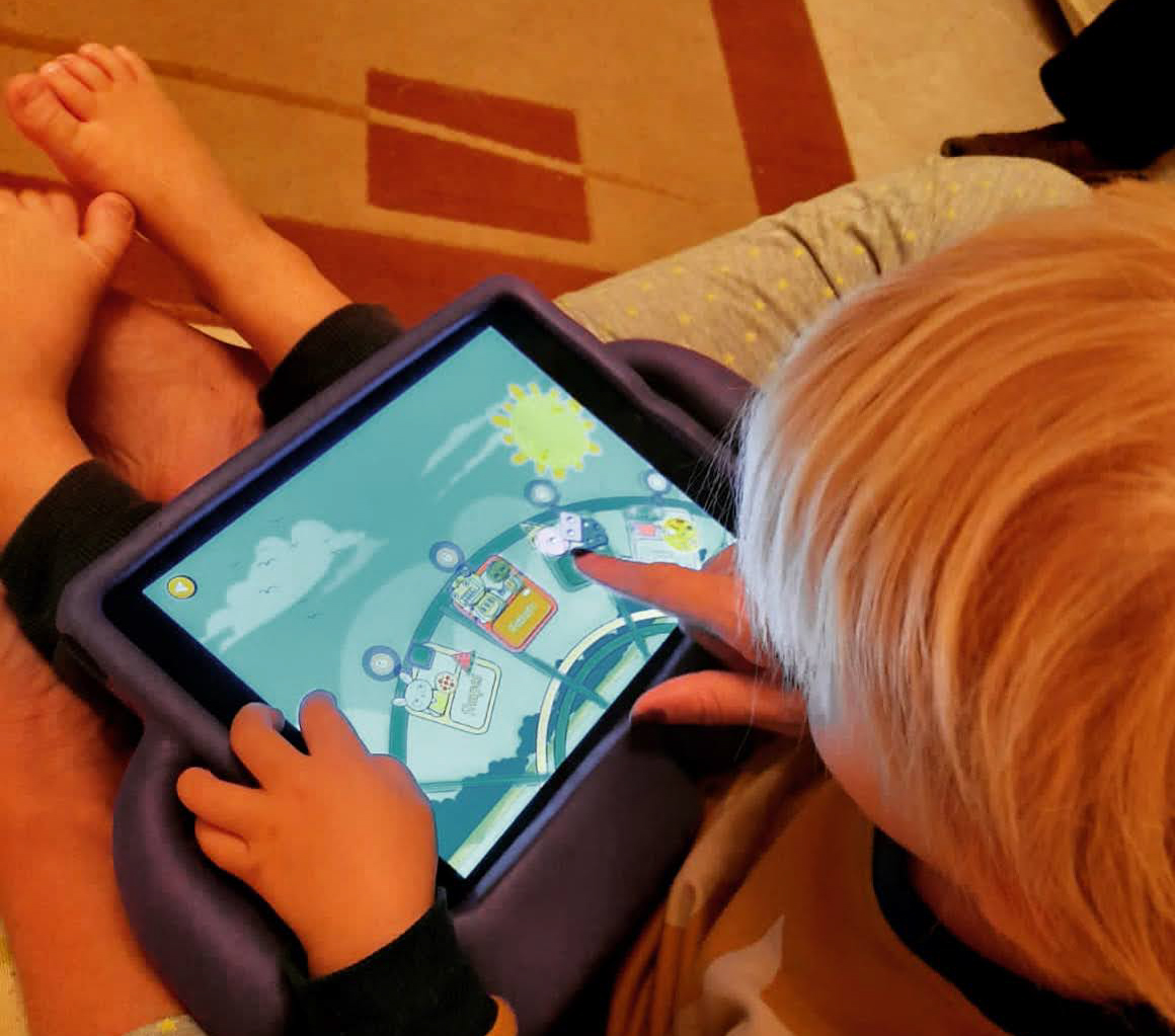 Young boy looking at an iPad, displaying an educational app
