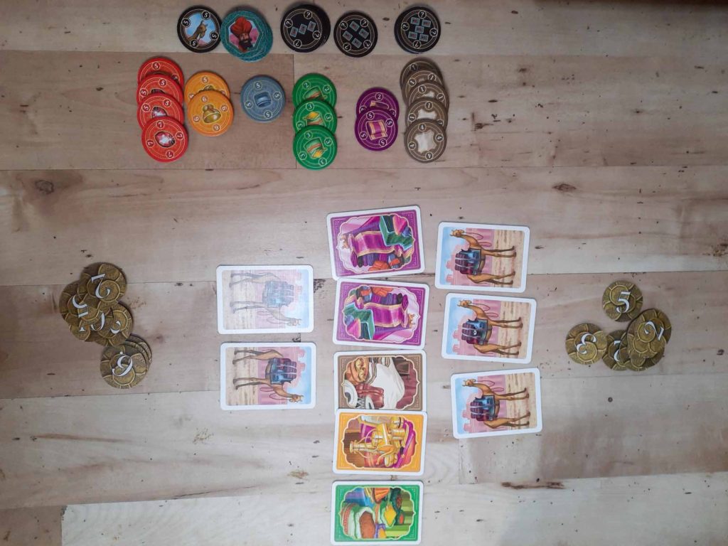 A top down view of the card game 'Jaipur', setup on a wooden floor