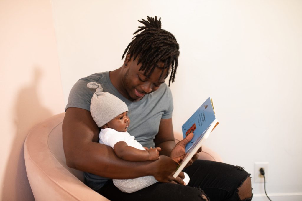 Man reading a book to a young child on his lap