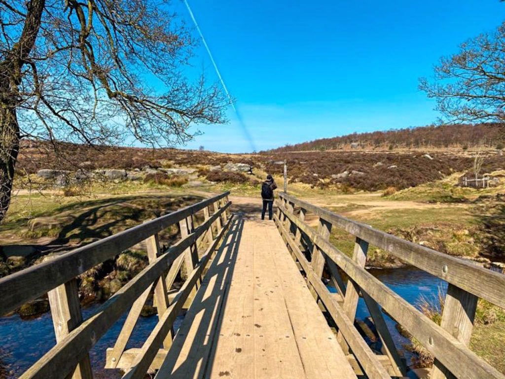 A wooden bridge over a river, with moorland behind
