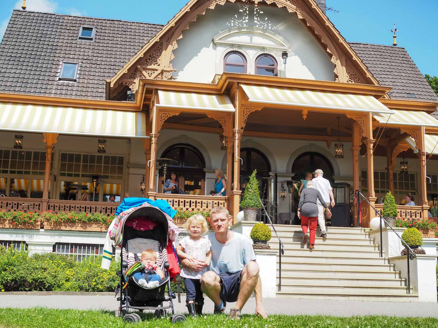 Family with pushchair in front of a decorative wooden building