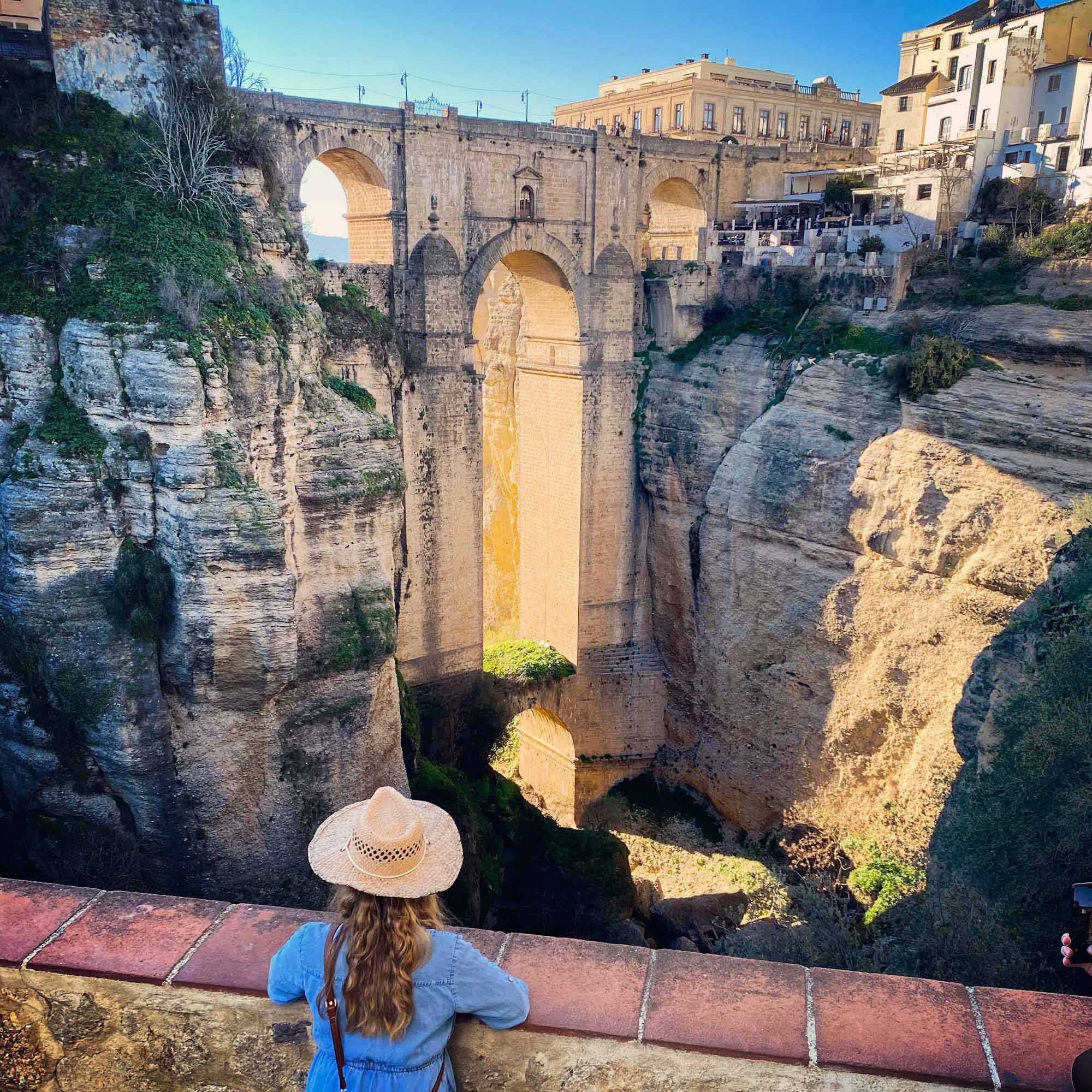 Lady stood at a viewpoint overlooking an impressive stone bridge spanning a canyon