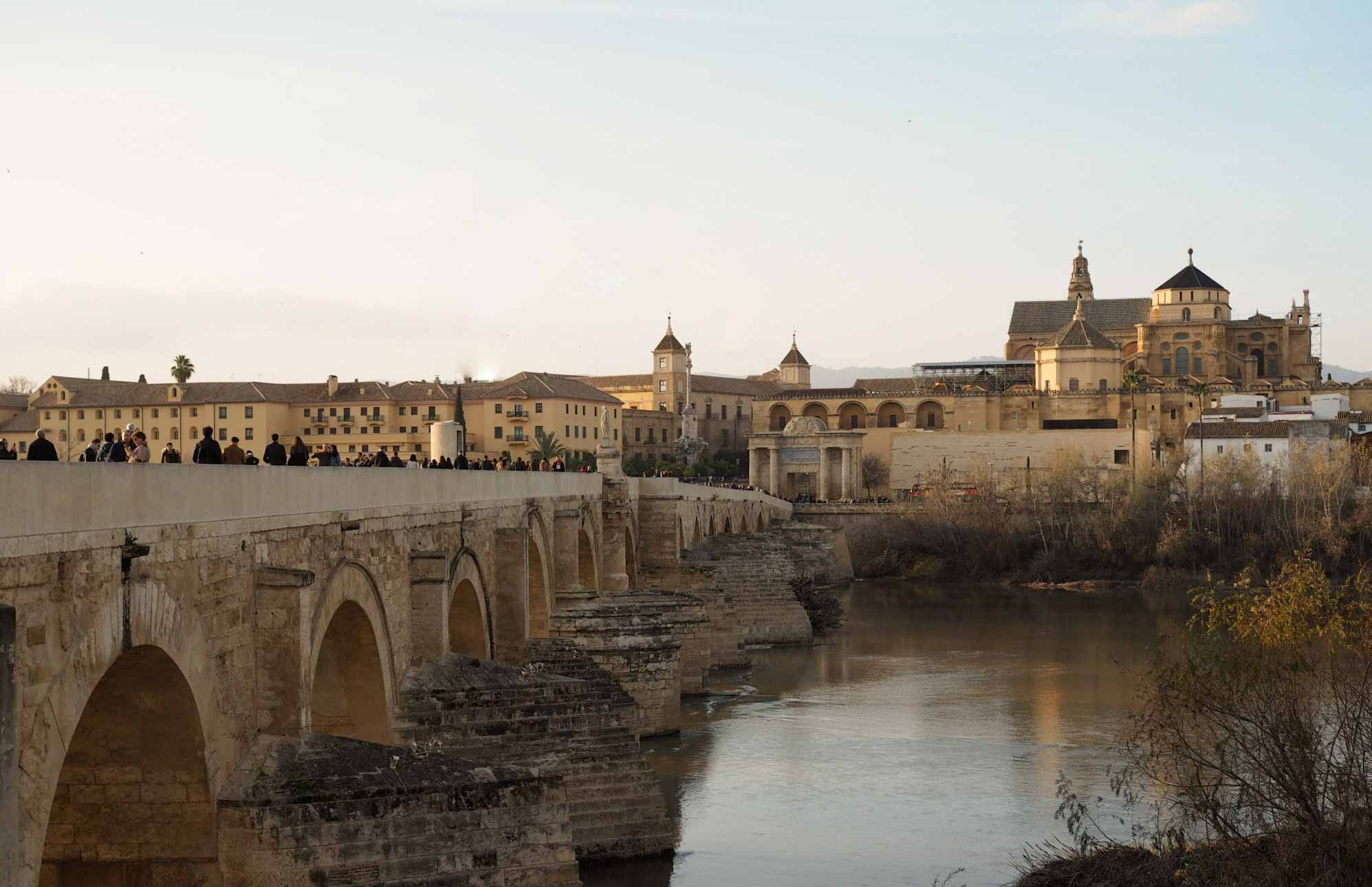 Old stone bridge across a river, with cathedral behind