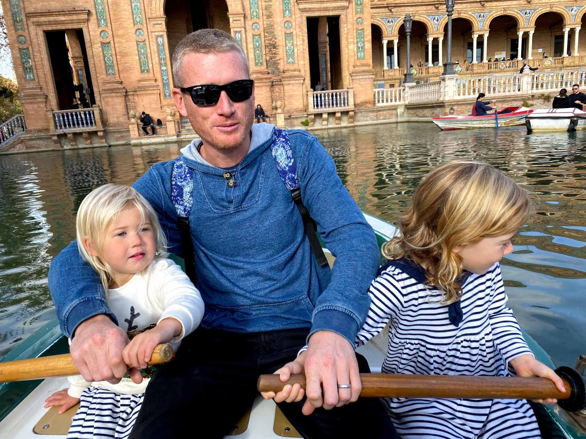 Father and 2 daughters rowing a boat on an ornamental lake