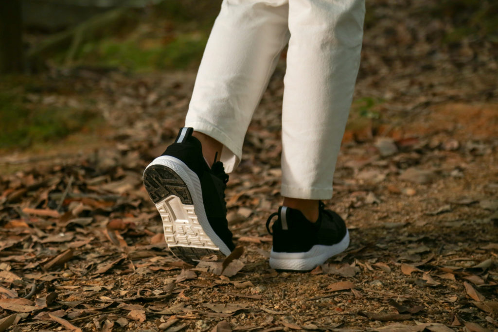Close up of black Loom Footwear trainers walking on leaves