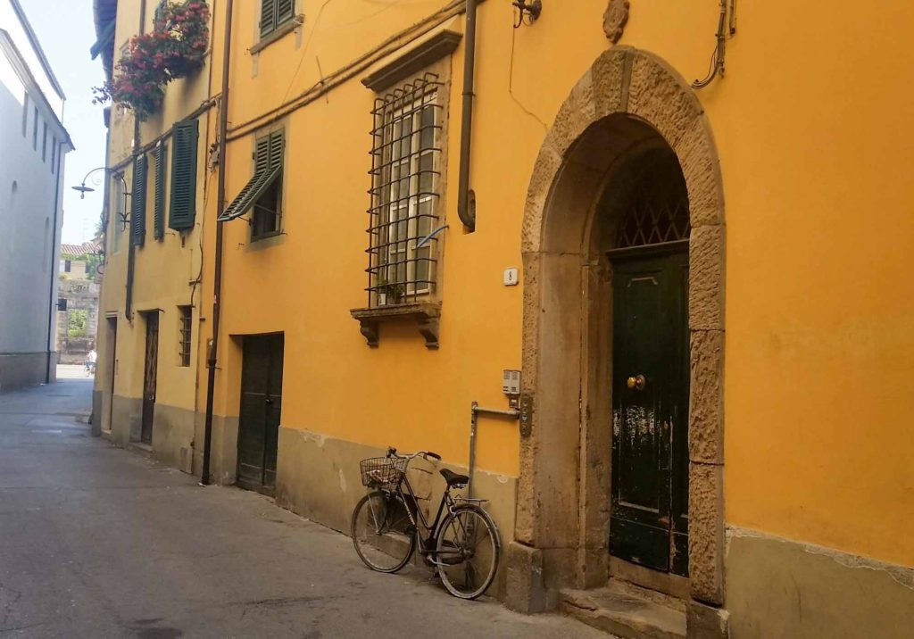 An orange painted traditional town house in Italy, with bike leant against the front wall