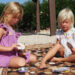 2 young girls sat outside playing the card game 'Dobble'